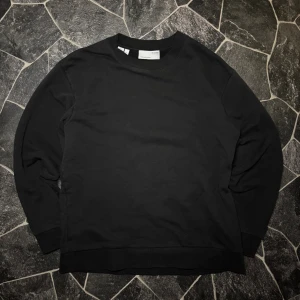 Selected Homme Sweatshirt - En stilren svart sweatshirt från Selected Homme i storlek S. Tröjan har rund hals, ribbade muddar vid hals, ärmslut och nederkant. Tillverkad i mjuk bomull som är skön mot huden. Perfekt för dig som gillar enkel och clean stil.