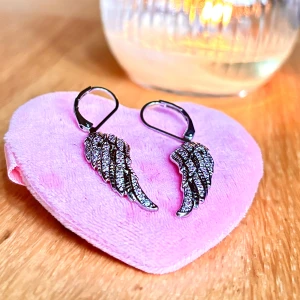 Trendiga vingformade örhängen med strass! - Trendiga vingformade örhängen i silverfärgad metall med strass. Höjd: 3 cm. Nya!