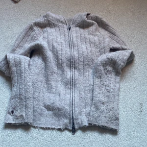 Beige stickad hoodie från 157, M - Mysig beige stickad hoodie från 157 i storlek M. Tröjan har dragkedja framtill, huva och ribbat mönster. Perfekt för kyliga dagar och enkel att matcha med jeans eller mjukisbyxor. Skulle säga att den är som en   Xs eller S