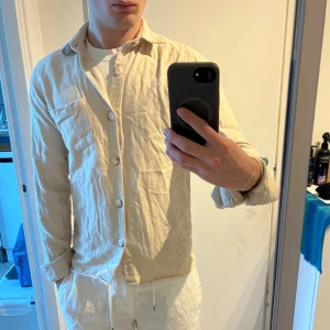 Beige överskjorta från Ciszere XS - Snygg beige skjorta från Ciszere i slim fit med klassisk krage och bröstficka. Skjortan har långa ärmar och knappar framtill. Materialet är mjukt och har en lätt struktur som ger en chill vibe. Perfekt för dig som gillar stilrena och enkla plagg.