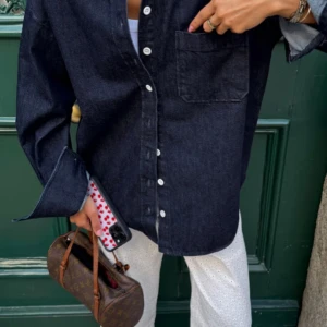 Mörkblå denimskjorta med knappar - Snygg mörkblå skjorta i denim med klassisk krage och vita knappar framtill