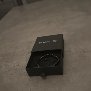 Svart pärlarmband från BVALDI - Stilrent svart armband från BVALDI med små runda pärlor och dekorativa fyrkantiga detaljer. Armbandet har justerbar knytning och levereras i exklusiv svart ask med logga. Perfekt accessoar för dig som gillar minimalistisk och modern stil. Använd 1 gång väldigt bra skick 