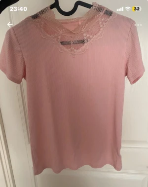 Rosa ribbad blus med spets från VRS - Supersöt ljusrosa ribbad blus från VRS Teen med korta ärmar och dekorativ spetskrage i rosa. Perfekt för dig som gillar romantiska detaljer och en feminin look. Mjuk och stretchig känsla, passar till många olika stilar.