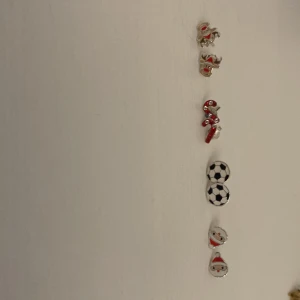 Set med juliga och sportiga örhängen - Säljer ett set med fem par örhängen i olika motiv: pepparkaksgubbe, ren, polkagris, fotboll och tomte. Färgerna är silver, röd, vit och svart. Perfekt för dig som vill ha roliga och unika örhängen till jul eller när du vill sticka ut.