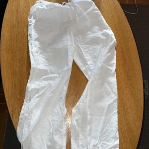 Vita linnebyxor från Gina Tricot - Snygga och luftiga vita linnebyxor från Gina Tricot med resår och snörning i midjan. Perfekta för varma dagar och har en avslappnad passform. Byxorna är tillverkade i linne och har raka ben för en chill vibe.