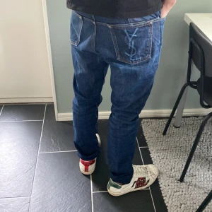 Blå jeans från Yves Saint Laurent - Snygga blå jeans från Yves Saint Laurent med tight passform. De har en klassisk femficksdesign och ett YSL-märke på bakfickan. Köpta för 3800kr!