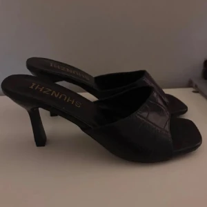 Svarta klackskor - Snygga svarta klackskor med öppen tå och låg klack från Shunzhih. Skorna är eleganta med fyrkantig tå. Perfekta för dig som gillar stilrena och trendiga skor.