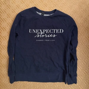 Mörkblå sweatshirt med texttryck - Mysig mörkblå sweatshirt från Amisu med vit text 'UNEXPECTED Stories' framtill. Tröjan har rund halsringning och långa ärmar, perfekt för en avslappnad stil. Tillverkad i mjuk bomullsmix för extra komfort.