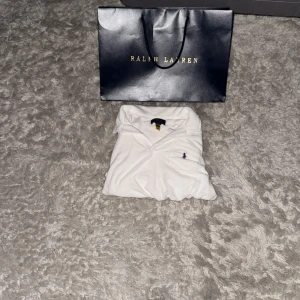 Vit piké från Polo Ralph Lauren - Vit pikétröja från Polo Ralph Lauren med klassisk krage och korta ärmar. Storlek 14-16. Helt oanvänd, nypris 1299 kr