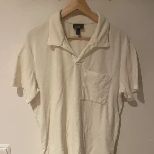 Vit frottéskjorta från H&M - Snygg vit skjorta från H&M i frottématerial med regular fit. Skjortan har korta ärmar, klassisk krage och en bröstficka som ger en chill vibe. Perfekt för dig som gillar enkel och clean stil.