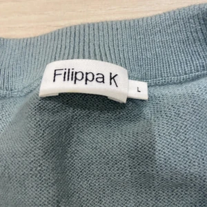 Ljusgrå stickad tröja från Filippa K - Snygg ljusgrå stickad tröja från Filippa K i storlek L. Tröjan har rund halsringning och långa ärmar, perfekt för lager-på-lager. Enkel och stilren design som passar till allt. Materialet är mjukt och skönt mot huden.