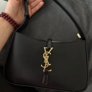Svart axelväska från Saint Laurent - Snygg svart axelväska från Saint Laurent med guldigt YSL-logo framtill. Ställ gärna frågor privat! 💕☺️