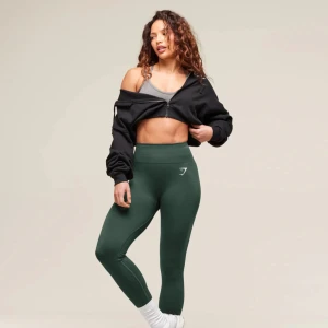 Gymshark tights - Mörkgröna tights från Gymshark som endast blivit använda ett par gånger. Det finns inga tecken på användning förutom att man kan se att själva loggan är lite ”sprucken” om man tittar nära, men som ni ser på bilden så finns hela loggan fortfarande där. 