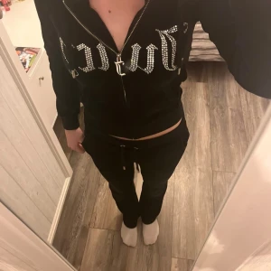 Juicy Couture svart hoodie med strass - Svart hoodie från Juicy Couture i mjuk velour med glittrande strassbokstäver över bröstet. Tröjan har huva, dragkedja framtill och fickor. Materialet är polyester med lite stretch för extra komfort. Nypris ligger på ungefär 1100kr. Går även att köpa hela setet och pris kan diskuteras då