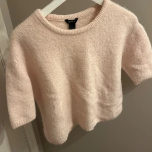 Ljusrosa stickad tröja  - Ljusrosa stickad tröja från Lindex. Tröjan har korta ärmar och rund halsringning