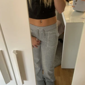 Grå mjukisbyxor Juicy Couture XXS - Supermysiga grå mjukisbyxor från Juicy Couture i velour med broderad JC-logga. Byxorna har snörning i midjan, fickor både fram och bak med snygga detaljer. 