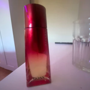 BOSS Intense parfymflaska röd - Snygg parfym från BOSS i röd flaska med texten 'Intense'. Perfekt för dig som vill sticka ut med en stilren och modern doftaccessoar. Volym och ingredienser syns ej på bilderna.