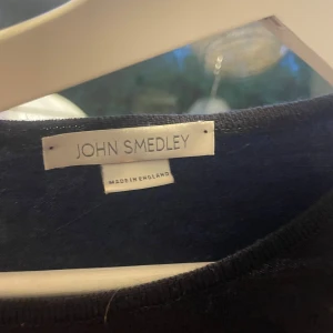 Lila långärmad tröja John Smedley - Säljer en stilren lila långärmad tröja från John Smedley, tillverkad i England. Tröjan har en klassisk rund hals och är gjord i mjukt material som känns skönt mot huden. Perfekt för dig som gillar minimalistisk och clean stil.