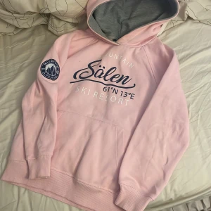 Rosa hoodie Sälen Ski Resort - Säljer en ljusrosa hoodie med tryck från Sälen Ski Resort. Tröjan har huva med grå insida, stor magficka och ett snyggt märke på ärmen. Perfekt för dig som gillar mysiga och sportiga vibes. Är i storlek 134/140 men känns nästan som en xs 