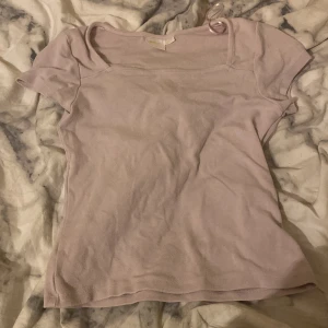 Ljusrosa kortärmad topp - Säljer en ljusrosa topp med korta ärmar och rundad hals. Toppen har en enkel och clean design, perfekt för att matcha med jeans eller kjol. Materialet känns mjukt och bekvämt mot huden. En basic topp som funkar till många olika stilar.