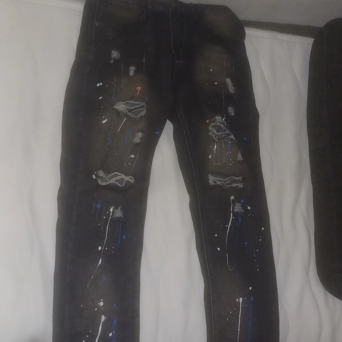 Svarta jeans med färgstänk och slitningar