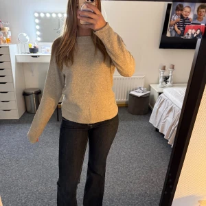 Beige stickad tröja med rund hals - Mysig beige stickad tröja med rund halsringning och långa ärmar. Tröjan har en enkel och clean look med ribbade muddar vid ärmslut och nederkant. Perfekt för lager-på-lager under kyliga dagar.