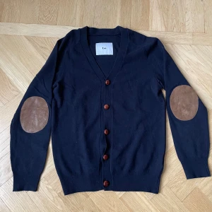 Blå Cardigan, use - Säljer en svinsnygg blå cardigan med läderpatches på armbågarna. Hör av er vid frågor!