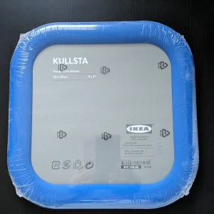 KULLSTA 23x23 cm - KULLSTA väggklocka från IKEA, design Chris Martin. Mått: 23x23 cm (9x9 tum). Produkten är helt ny, fortfarande i originalförpackning med skyddsplast kvar. Modern design med blå ram, perfekt för hemmet eller kontoret.