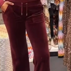 Vinröda velourbyxor med snörning - Snygga vinröda mjukisbyxor i mjuk velour med bootcut-ben och snörning i midjan. Byxorna har fickor fram och bak, samt bred resår i midjan för extra komfort. Perfekta för en chill och trendig look.