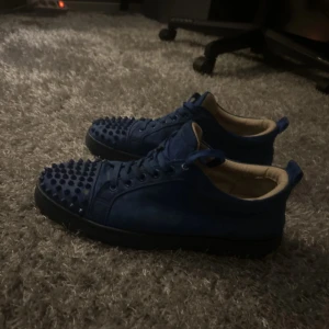 Blå sneakers med röd sula - Säljer ett par riktigt snygga blå sneakers med cool röd sula. Skorna har snörning och en sportig vibe, perfekta för dig som vill sticka ut. Ovandelen är helblå och sulan har en unik röd färg som verkligen poppar.