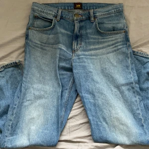 Lee ljusblå raka jeans W31 L32 - Ljusblå jeans från Lee i modellen Oscar med klassisk femficksdesign och raka ben. Jeansen har normal passform och är tillverkade i bomull. Snyggt slitna detaljer och Lee-logga på bakfickan. Perfekta för en avslappnad stil.