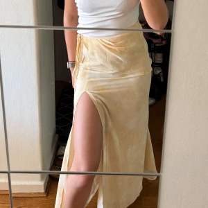 Gul kjol med slits från Adoore - Superfin långkjol i ljusgult från Adoore med slits och knyt i sidan. Helt ny med prislapp, Storlek 36.