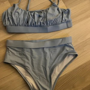 Ljusblå bikini från SHEIN, S - Snygg ljusblå bikini från SHEIN i storlek S. Överdelen har smala axelband och rynkade detaljer framtill, medan underdelen är högt skuren med bred resår i midjan. Perfekt för strandhäng och pooldagar!