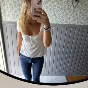 Vit blus med knappar och kort ärm - Säljer en söt vit blus med korta ärmar och rundad hals. Toppen har knappar framtill och ett lätt rynkat parti under bysten 