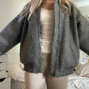 Grå teddy bomberjacka med dragkedja - Säljer en trendig grå teddy bomberjacka från H&M med oversized passform. Bra skick bara använd fåtal gånger❤️storlek s/xs