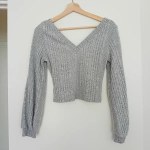 Grå ribbad stickad tröja - Superfin grå stickad tröja från Shein med ribbat mönster och v-ringad hals. Tröjan har lång ärm och är lite croppad, perfekt till jeans eller kjol. Mjuk och skön, passar dig som gillar enkel men snygg stil.