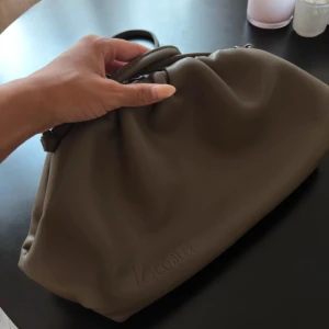 Beige axelväska från V.Cobler - Säljer en snygg beige axelväska från V.Cobler i mjukt skinn. Väskan har en puffig, slouchy form med dragsko och stilren design. Perfekt storlek för det viktigaste och enkel att bära över axeln. Logga diskret präglad på framsidan.