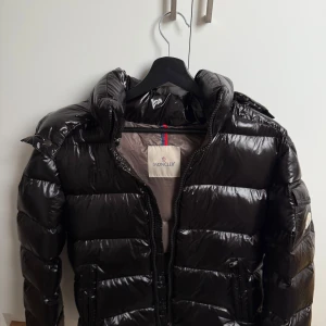 Moncler vinterjacka  - Säljer en svart, glansig pufferjacka från Moncler med klassisk logga på ärmen. I storlek S, med vissa tecken på användning. Perfekt för kalla dagar och riktigt snygg streetstil. Pris kan diskuteras vid snabb affär! 