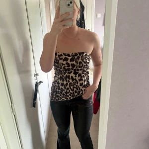Leopard tubtopp - Snygg tubtopp med leopardmönster i beige och bruna toner. Toppen är axelbandslös och har en lätt glansig satinlook. Sneskuren. Är strl M men skulle säga att den även kan passa en större S. Fråga gärna vid fundering😊Aldrig använd