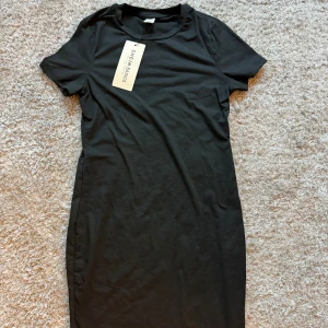 Svart t-shirtklänning från SHEIN - Enkel svart t-shirtklänning från SHEIN med rund hals och korta ärmar. Klänningen har en rak passform.