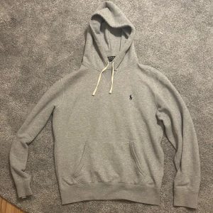 Grå hoodie från Polo Ralph Lauren - Snygg grå hoodie från Polo Ralph Lauren med klassisk broderad logga på bröstet. Väldigt bra tröja nu när det börjar bli lite kallare❄️ny pris: 2000+kr. 9,5/10 skick inte använt så mycket.