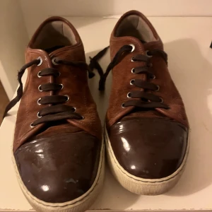Bruna sneakers från Lanvin i mocka - Mina gamla brun/orangea lanvins som inte använts på ett tag. Har rengjort och tvättat efter bilden så dem är så gott som nya k princip. Pris kan diskuteras