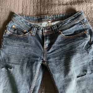 Blå bootcut jeans med slitningar - Säljer dessa blå lågmidjade bootcut-jeansen som jag själv har klippt hål i. Det står inte storleken, men skulle säga att det är storlek 36-38! Om ni har några frågor är det bara att höra av sig!💕säljer för 200kr, men priset kan diskuteras!