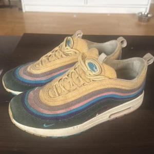 Nike Air Max 1/97 Sean Wotherspoon - Unika Nike Air Max 1/97 Sean Wotherspoon sneakers i manchester med vågiga paneler i gult, grönt, blått, rosa och lila. Skorna har snörning, rund tå och synlig Air Max-sula. Broderad detalj på hälen och ikonisk våglogga på plösen. Perfekta för dig som gillar färg och retrostil. Måttligt använda och har viss slitage (mest invändigt). Från Kickwho