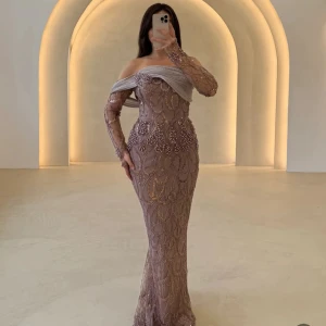 Champagnefärgad långklänning med pärlor - Säljer en elegant långklänning i champagnefärg med glittriga pärldetaljer och broderade mönster. Klänningen har offshoulder-design, transparenta långärmar och en lyxig omlott över bysten. Perfekt för bal eller nyår, riktigt statement-plagg!