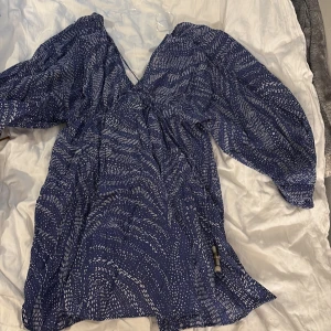 Blå mönstrad kortklänning med pärlor - Säljer en jätte fin strandlänning då den inte kommer till aldvändning jätte smidig på när man är utomlands ❤️❤️❤️