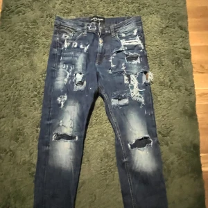 Blå ripped jeans Supply & Demand XS - Säljer ett par blå jeans från Supply & Demand i storlek XS med rejält slitna och trasiga detaljer framtill. Jeansen har skinny passform och klassisk femficksdesign. Perfekta för dig som gillar en edgy streetstil.