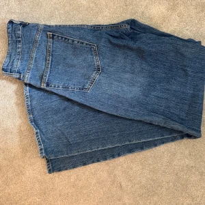 Blå raka jeans med klassisk look mid waist - Säljer ett par blå jeans med rak passform och klassisk femficksdesign. Jeansen har en normal midja och är tillverkade i slitstarkt denimtyg. Perfekta för dig som gillar en tidlös och enkel stil.