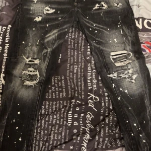 Svarta dsquared2 jeans  - Riktigt snygga svarta jeans med slitningar, hål och coola färgstänk över hela byxorna. Jeansen har en lite tvättad look och flera trasiga detaljer på benen för en edgy streetstyle. Perfekta för dig som gillar en rå och trendig stil. Säljs ej längre och pris kan diskuteras