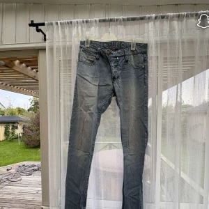 Ljusblå skinny jeans från HUMÖR - Säljer ett par ljusblå skinny jeans från HUMÖR med klassisk femficksdesign och snygga slitningar. Jeansen har låg midja och är tillverkade i mjukt bomullsjeansmaterial. Perfekta för dig som gillar en smal passform och stilren look.